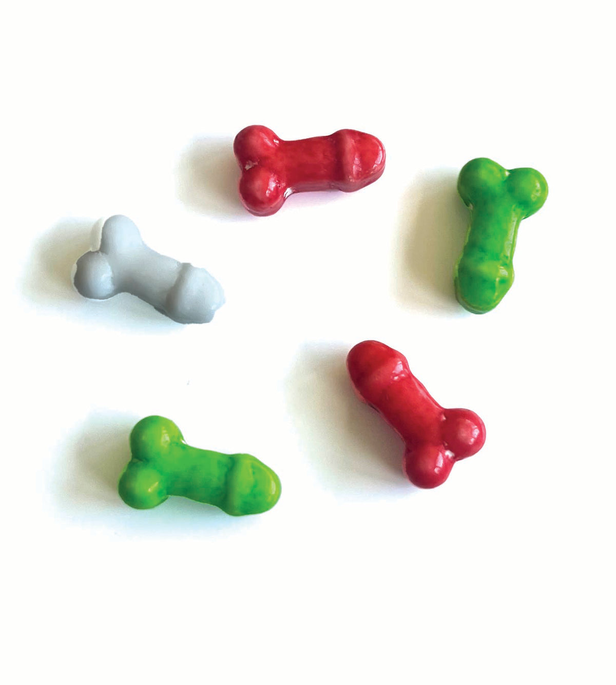 Red, white, and green penis-shaped Christmas candies on a white background