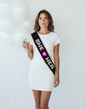 Littlegenie.com black bridal sash with glittery "SHE + HER" text and pink heart. Rainbow trim.